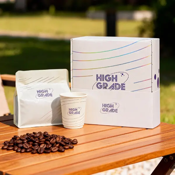 Individuelle Kaffeebox mit passendem Kaffeebeutel und Pappbecher, die draußen auf einem Holztisch ausgestellt ist