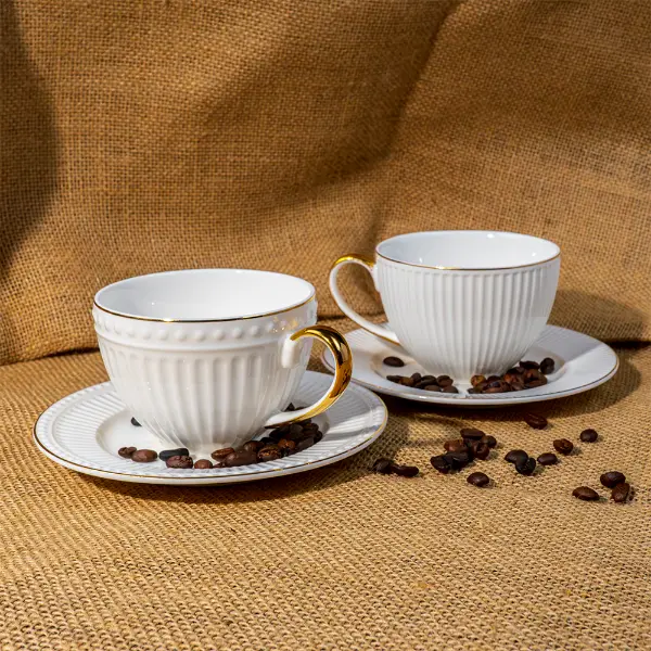 Individuell geprägte Keramiktasse mit goldenem Griff und passender Untertasse