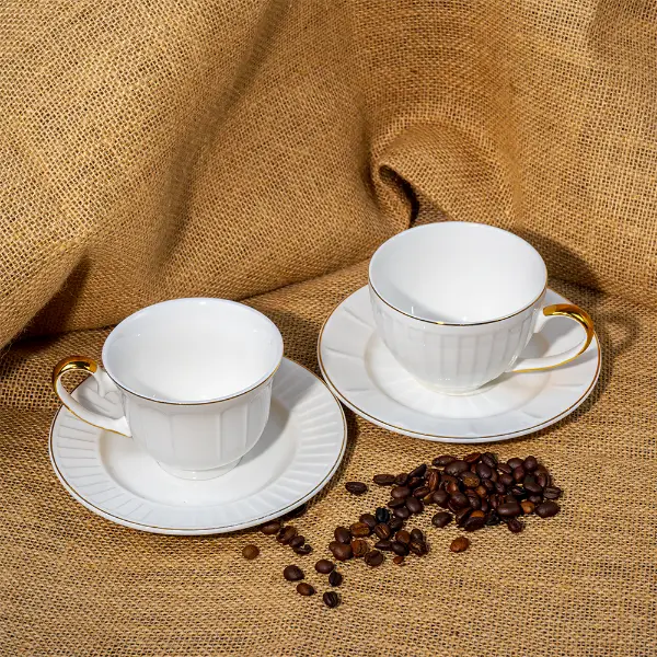 Individuell goldbemalte, geprägte Keramiktasse mit Untertasse, präsentiert mit Kaffeebohnen