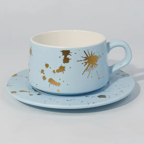 Seitenansicht einer goldblattfarbenen Keramik-Kaffeetasse mit handbemaltem Spritzer-Design