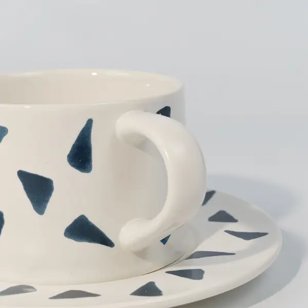 Nahaufnahme des Griffs einer bedruckten keramischen Kaffeetasse mit dekorativem Druck